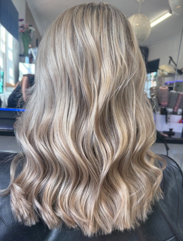 Long ash blonde hair styled in loose waves, seen from behind