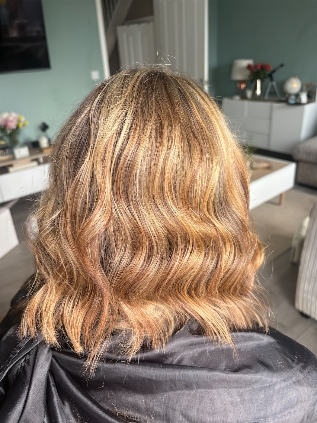 Shoulder-length hair with warm honey balayage and soft waves, seen from behind